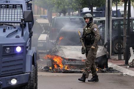 Zvecan, Kosovo. 26th May, 2023. A Kosovo Police Special Unit officer walks near a burning car in Zvecan, Kosovo, on May 26, 2023. Clashes between ethnic Serbs and Kosovo Police began after the Serbs gathered in front of the municipality building trying to block the entrance to recently-elected officials. Photo: Stringer/PIXSELL Credit: Pixsell/Alamy Live News 
